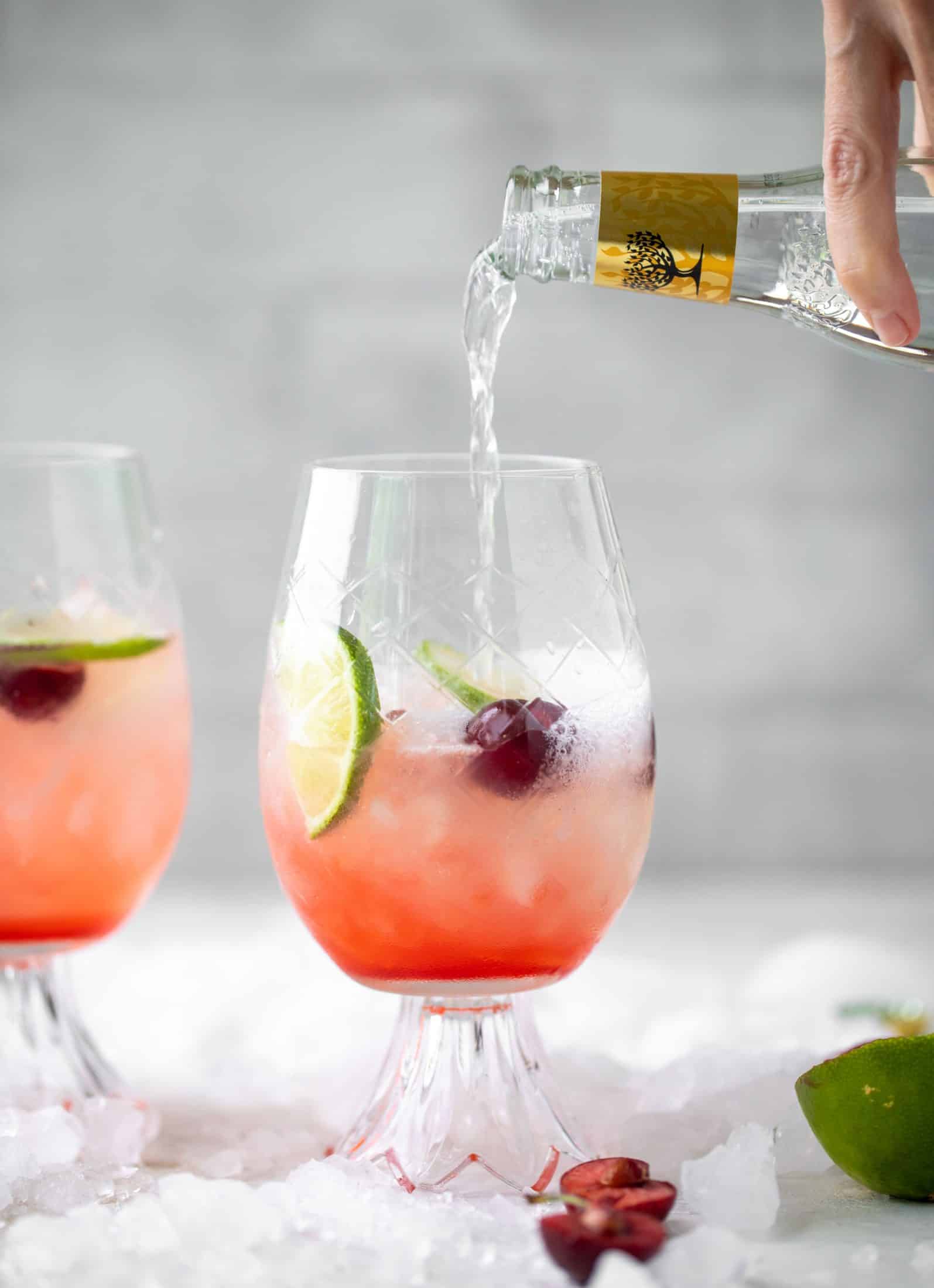 pouring tonic water into cherry gin and tonic